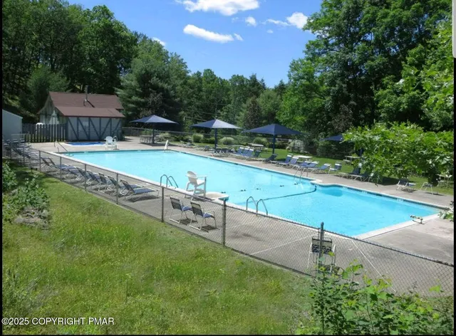a view of swimming pool with seating area and trees in the background