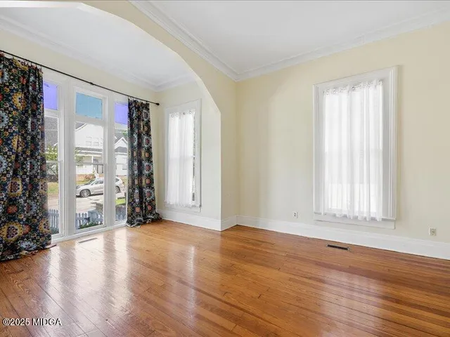 a view of an empty room with window and wooden floor