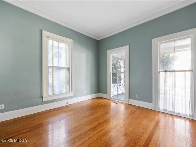 an empty room with wooden floor and windows