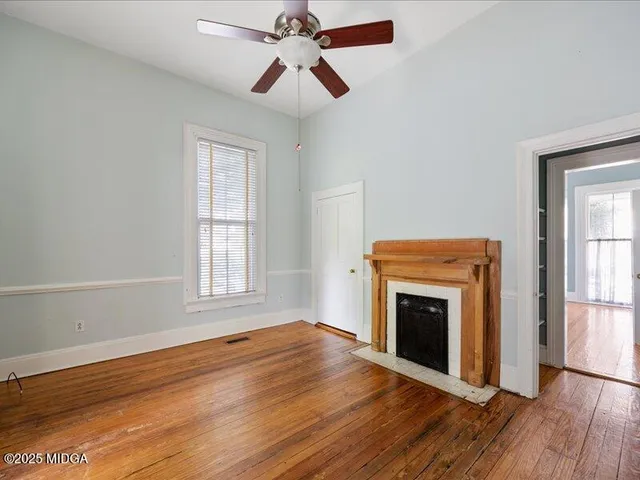 an empty room with windows fireplace and wooden floor