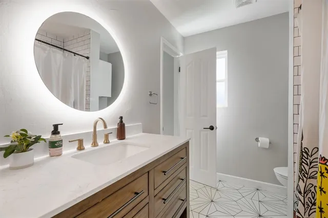 a bathroom with a sink a mirror a vanity and a shower
