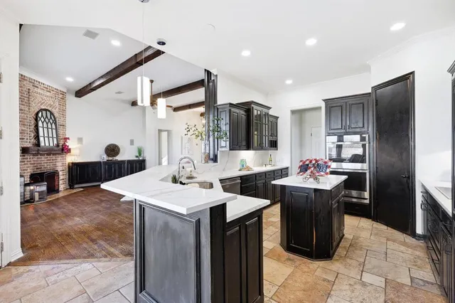 a kitchen with stainless steel appliances kitchen island granite countertop a refrigerator and a sink