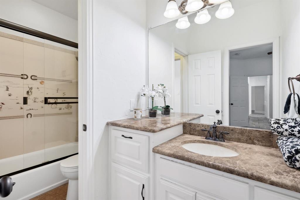 12886 St John Road Pilot Point, TX 76258 - Photo 24 of 35 a bathroom with a granite countertop sink a mirror and a shower