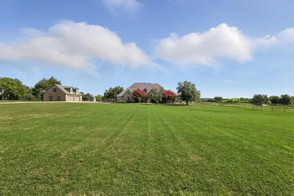 a view of a house with a big yard and large tree