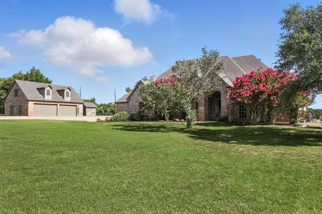 a view of a house with a big yard and large trees