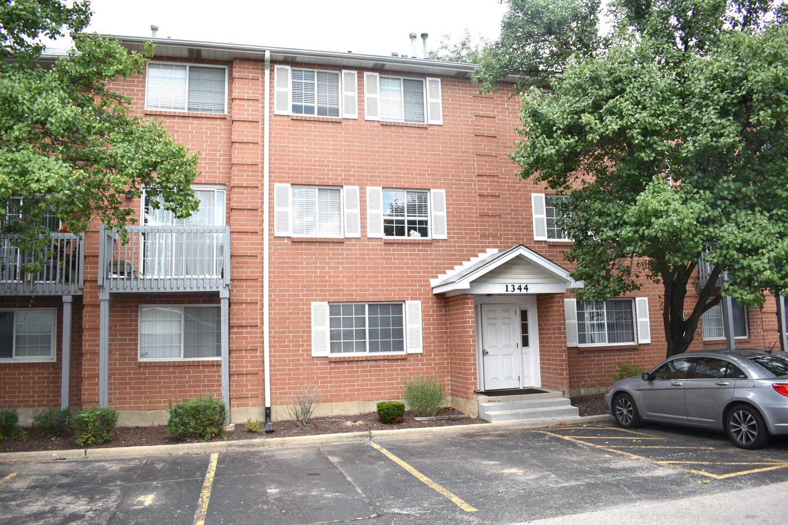 1344 South Lorraine Road, Unit F Wheaton, IL 60189 - Photo 1 of 27 a front view of a house with a yard and parking