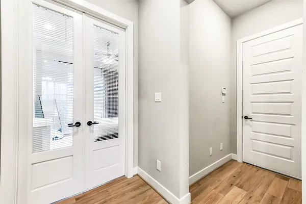an empty room with wooden floor fan and windows