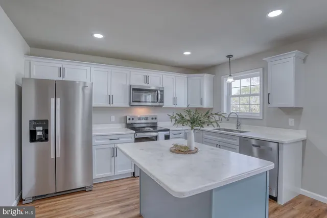 a kitchen with a sink a stove a refrigerator and white cabinets