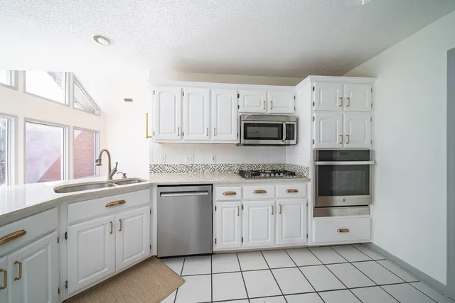 a kitchen with white cabinets and appliances