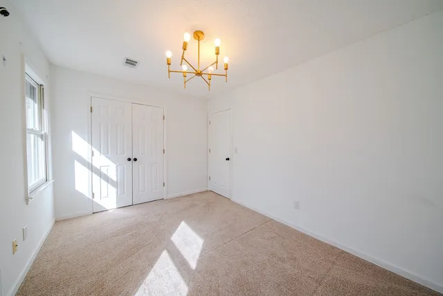 an empty room with windows and chandelier fan