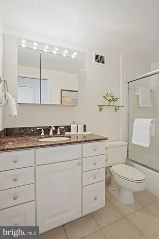 a spacious bathroom with a granite countertop sink a toilet and a mirror