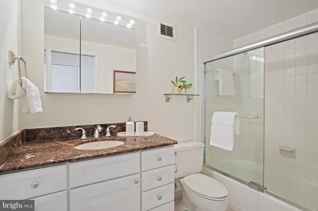a bathroom with a granite countertop sink a toilet a mirror and shower