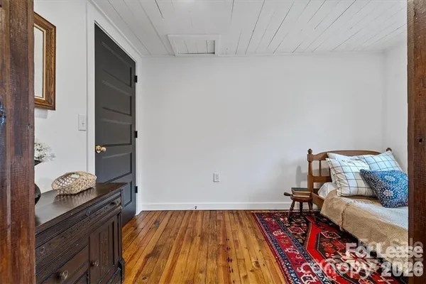a bed sitting in a bedroom next to a window and wooden floor