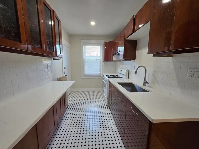 a kitchen with a sink a stove cabinets and a wooden floor