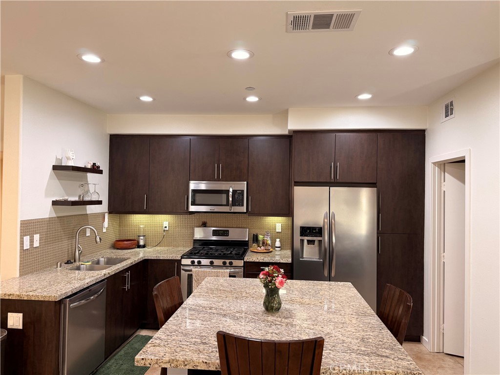 2230 Indus Way San Marcos, CA 92078 - Photo 6 of 26 a kitchen with stainless steel appliances kitchen island granite countertop a sink refrigerator and cabinets