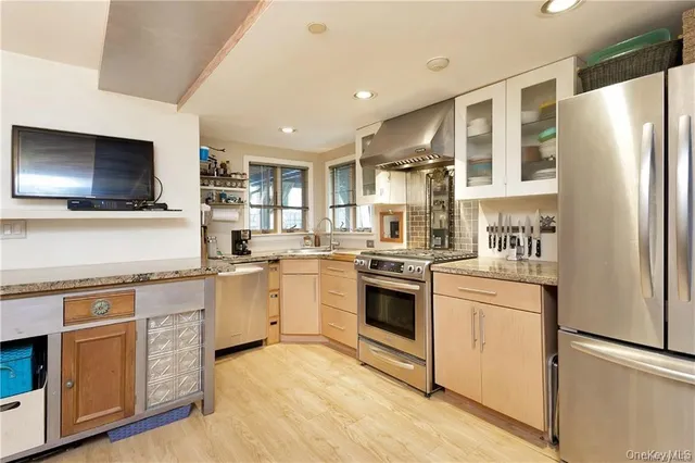 a kitchen with stainless steel appliances granite countertop a stove top oven a sink and a refrigerator