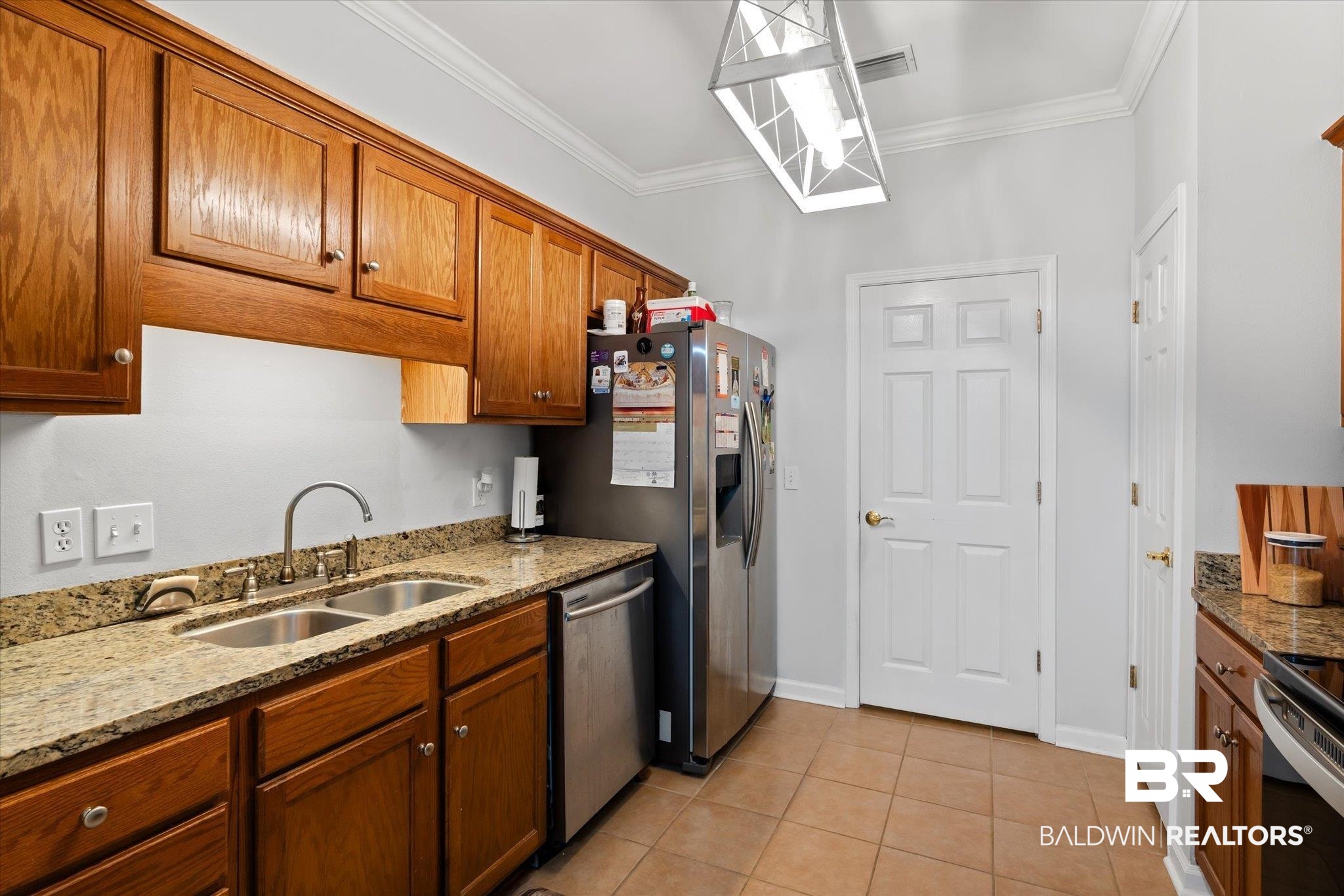3876 Emerille Drive Foley, AL 36535 - Photo 12 of 31 Kitchen featuring sink, light tile patterned flooring, crown molding, light stone countertops, and appliances with stainless steel finishes
