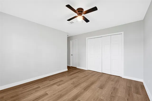 an empty room with wooden floor and ceiling fan