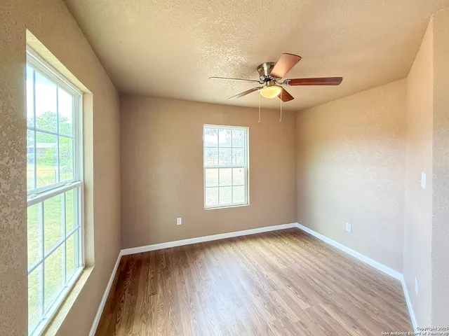 a view of empty room with wooden floor and fan