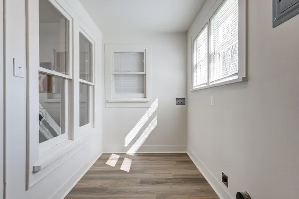 a view of an empty room with wooden floor and a window