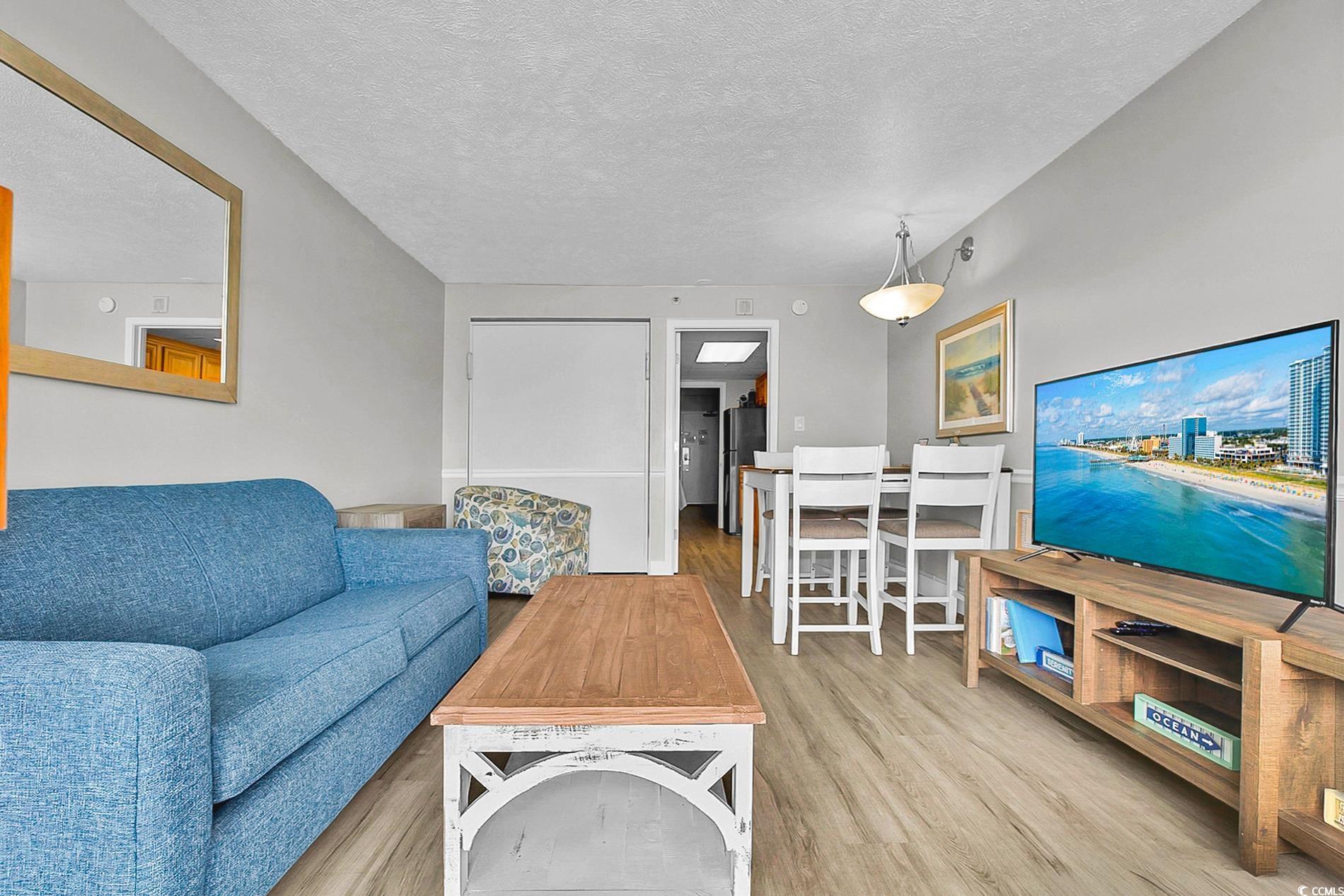 7200 North Ocean Boulevard, Unit 553 Myrtle Beach, SC 29572 - Photo 4 of 27 Living area featuring wood finished floors, a textured ceiling, and expansive windows