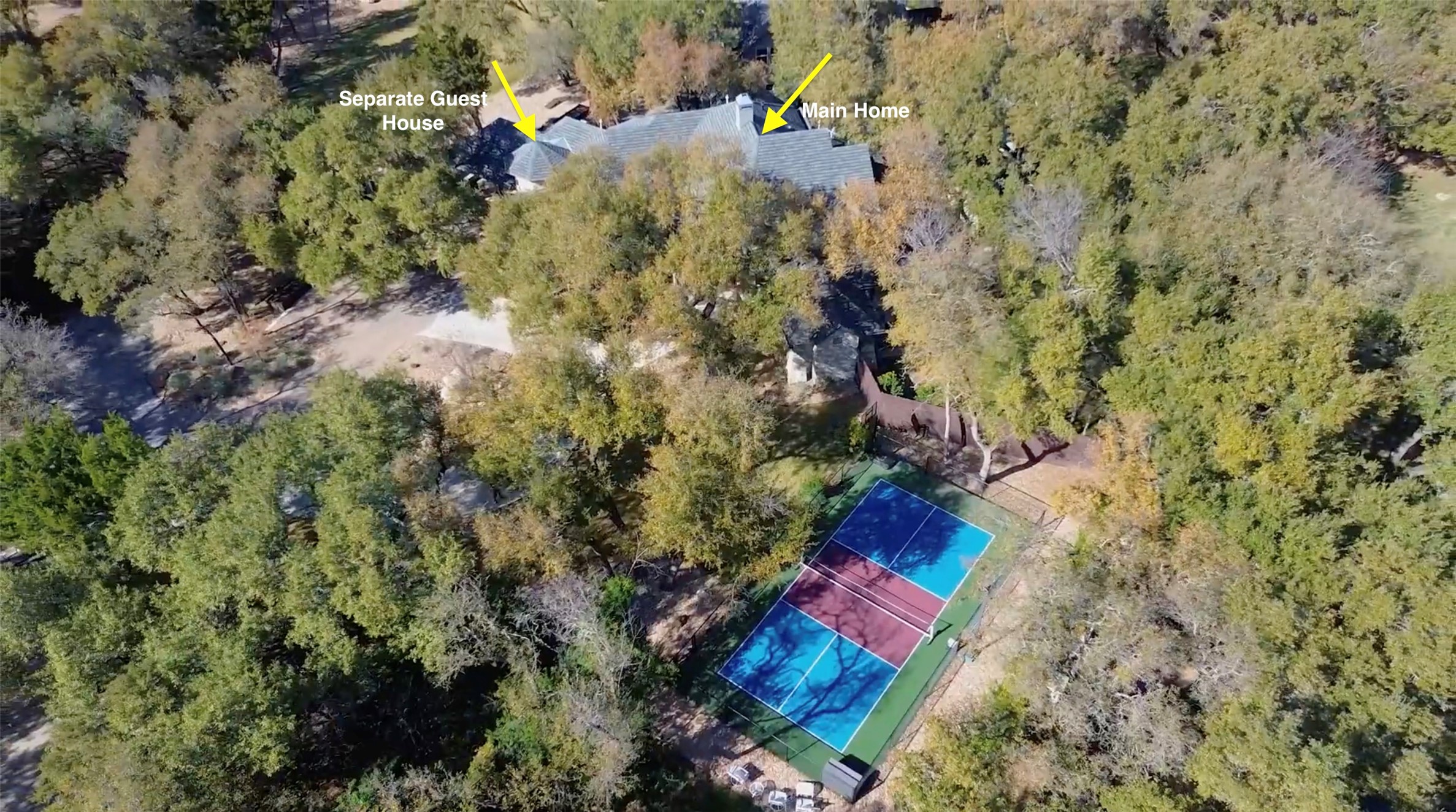 Expansive private grounds featuring a main home, separate guest house, and a dedicated sports court with fenced perimeter