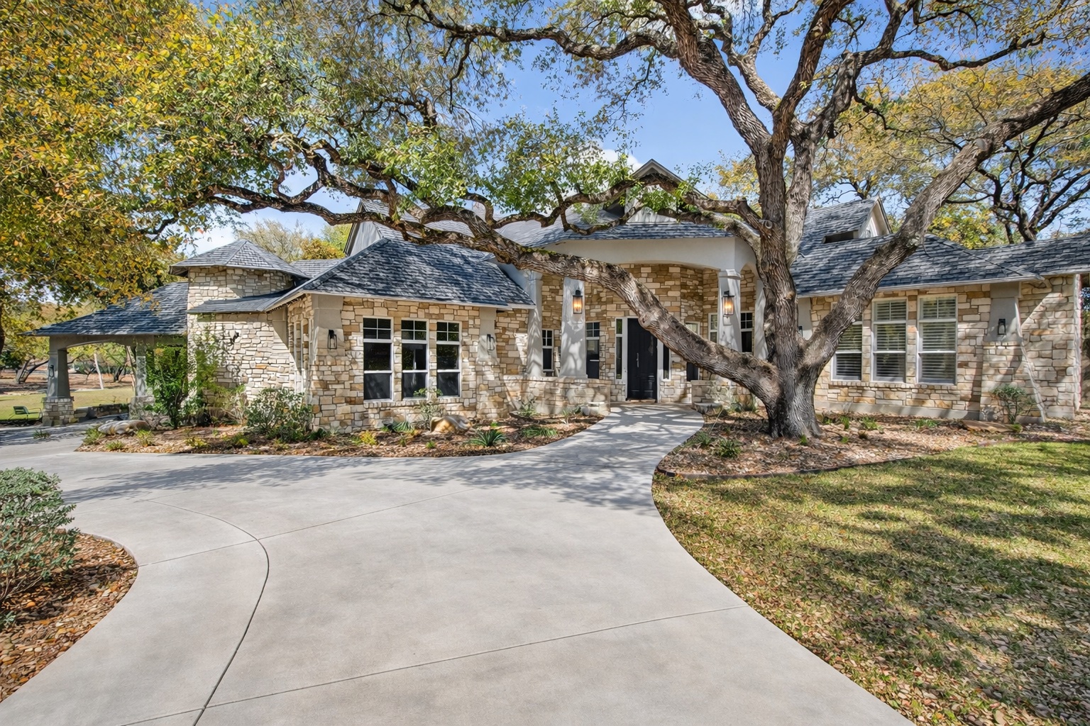 3627 Stoneridge Road Austin, TX 78746 - Photo 2 of 40 View of front facade with stone siding, a front yard, a high end roof, and driveway