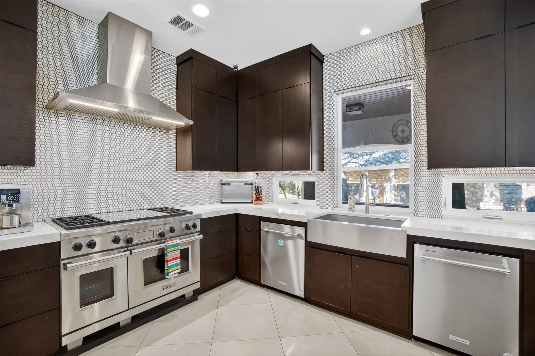 3627 Stoneridge Road Austin, TX 78746 - Photo 7 of 40 Kitchen with dark wood finish cabinets, stainless steel appliances, tasteful backsplash, light tile patterned floors, and recessed lighting