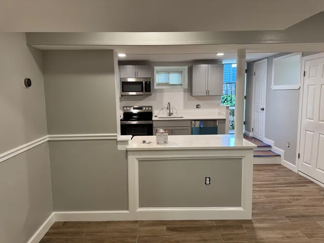 a view with cabinets a sink and wooden floor