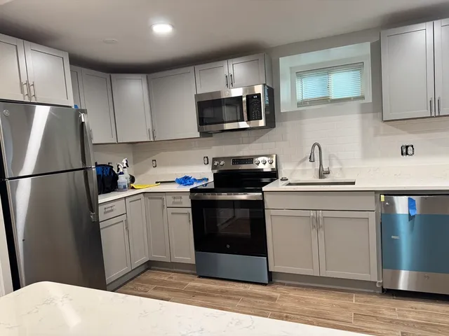 a kitchen with stainless steel appliances granite countertop a refrigerator stove a sink dishwasher and a microwave oven on the wooden floor