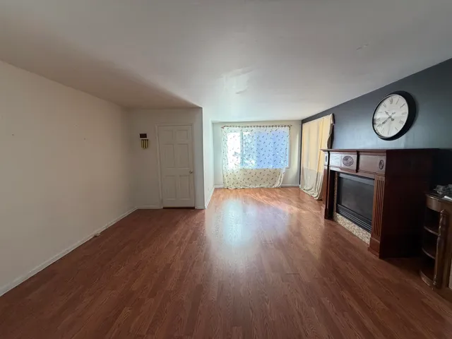 an empty room with wooden floor a fireplace and windows