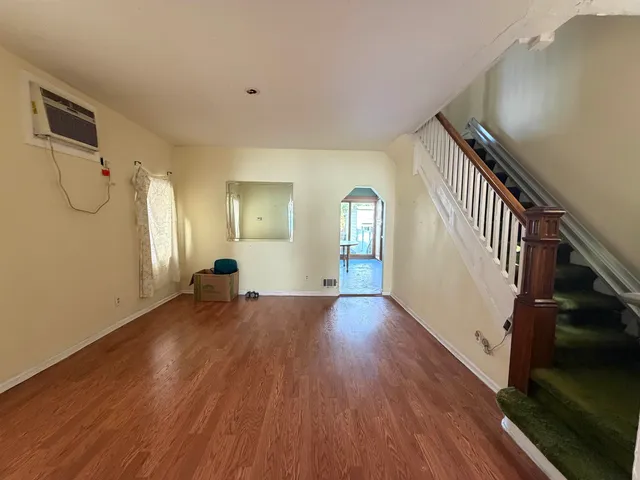 a view of empty room with wooden floor and fan