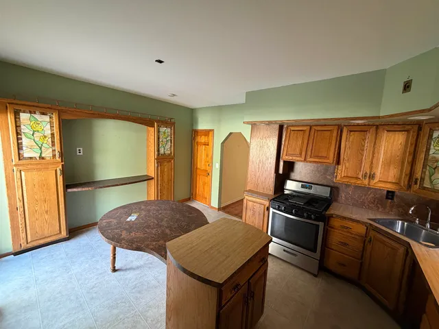 a living room with stainless steel appliances furniture a rug and a window