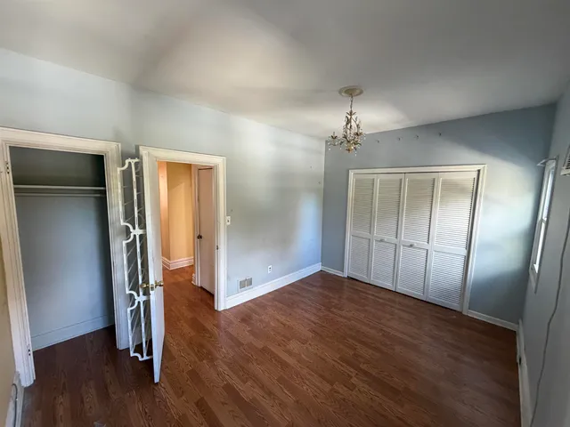 an empty room with wooden floor and hallway