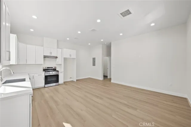 a large kitchen with granite countertop a large counter top a sink stainless steel appliances and cabinets