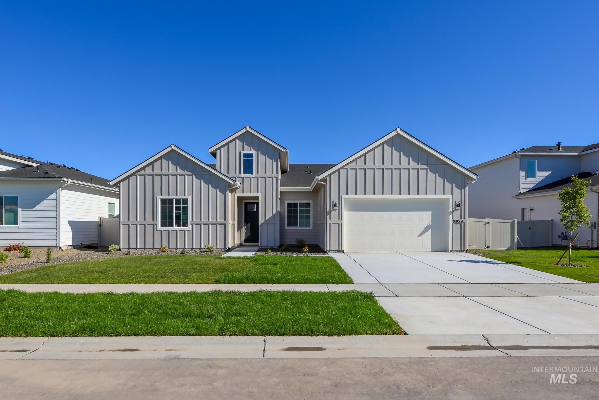 9074 West Moonglade Street Star, ID 83669 - Photo 1 of 40 Contemporary single-story residence featuring light gray board and batten siding, a prominent two-car garage, and a dark entry door