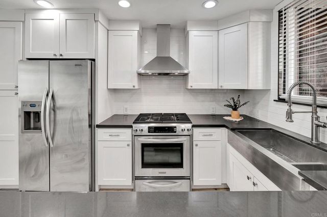 a kitchen with stainless steel appliances granite countertop a stove a refrigerator and a sink