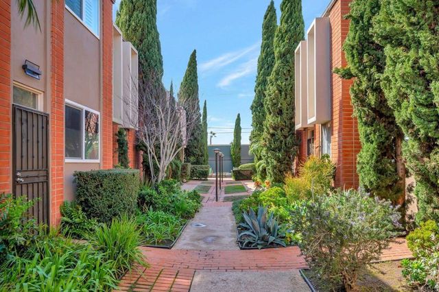 a large white kitchen with stainless steel appliances kitchen island granite countertop a table chairs in it and wooden floors