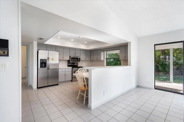 a kitchen with stainless steel appliances kitchen island granite countertop a table chairs sink and cabinets