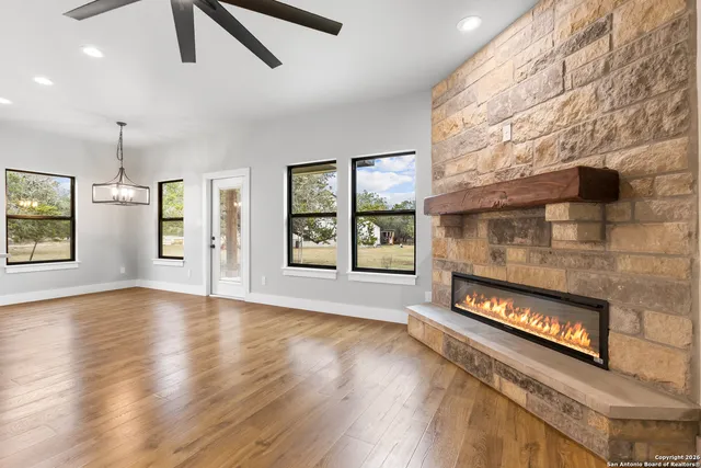a view of an empty room with window and wooden floor
