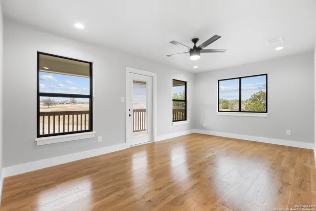 a view of an empty room with a window and wooden floor
