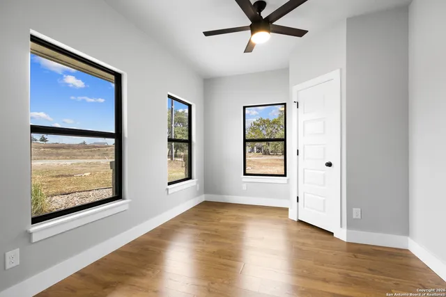 a view of an empty room with window and wooden floor