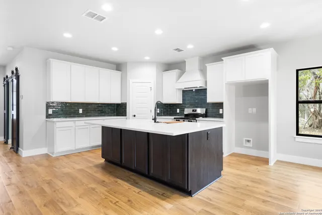 a kitchen with stainless steel appliances granite countertop a stove a sink dishwasher and a refrigerator with wooden floor