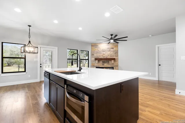 a kitchen with a stove a sink and wooden floor