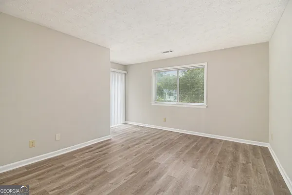 an empty room with wooden floor and windows