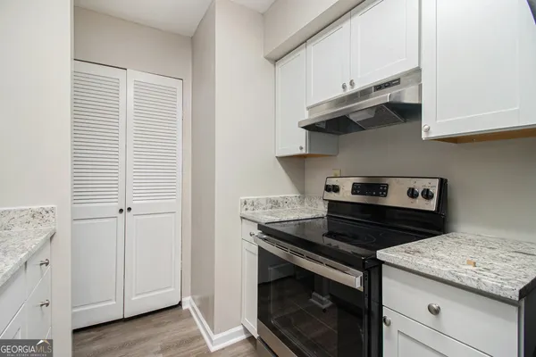a kitchen with stainless steel appliances granite countertop white cabinets and a stove
