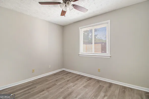 a view of empty room with wooden floor and fan