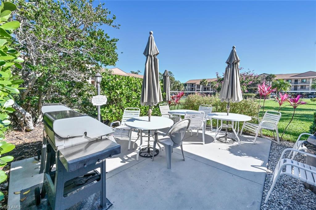 7300 St Ives Way, Unit 5208 Naples, FL 34104 - Photo 30 of 37 a view of a patio with a table and chairs and a small yard