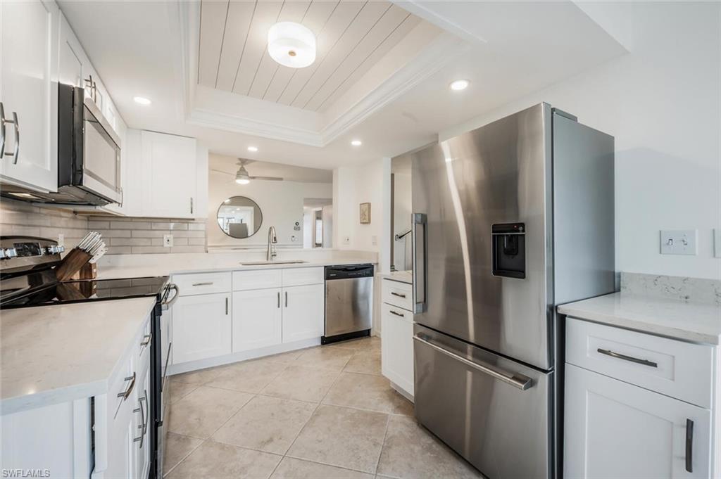 7300 St Ives Way, Unit 5208 Naples, FL 34104 - Photo 8 of 37 a kitchen with a refrigerator sink and cabinets