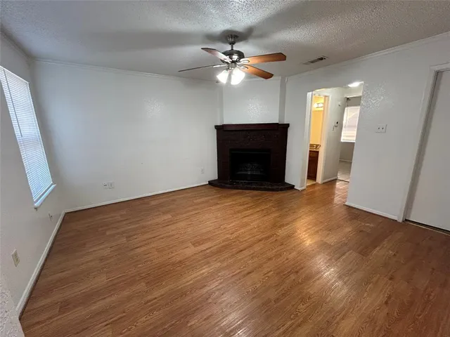 an empty room with wooden floor fan and windows